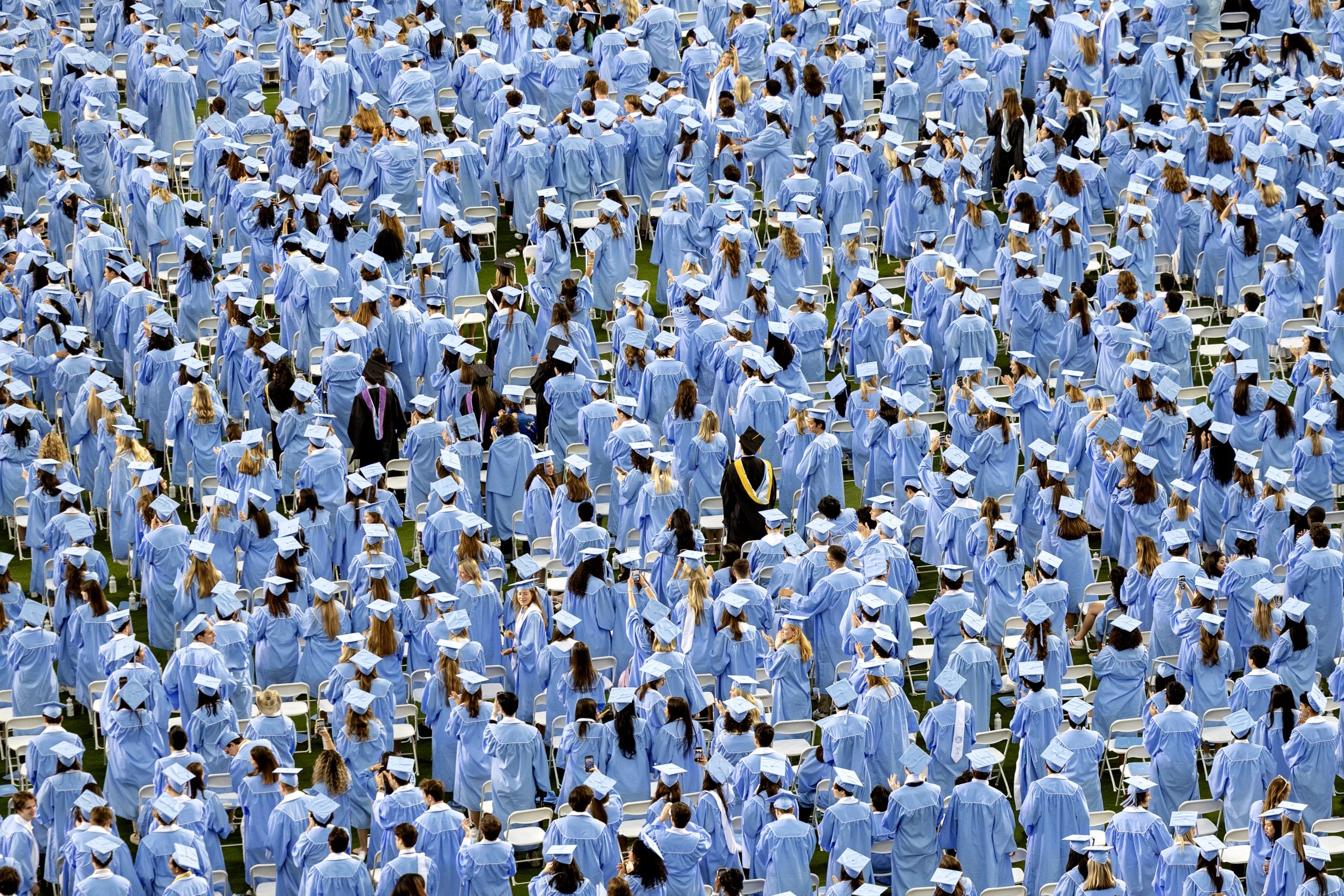 Graduates stand on the field at Kenan Stadium during 2025 Spring Commencement. 