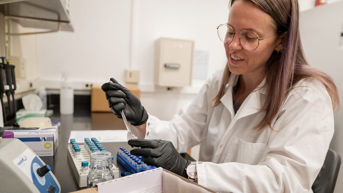 A scientist uses a syringe to put liquid in a test tube.