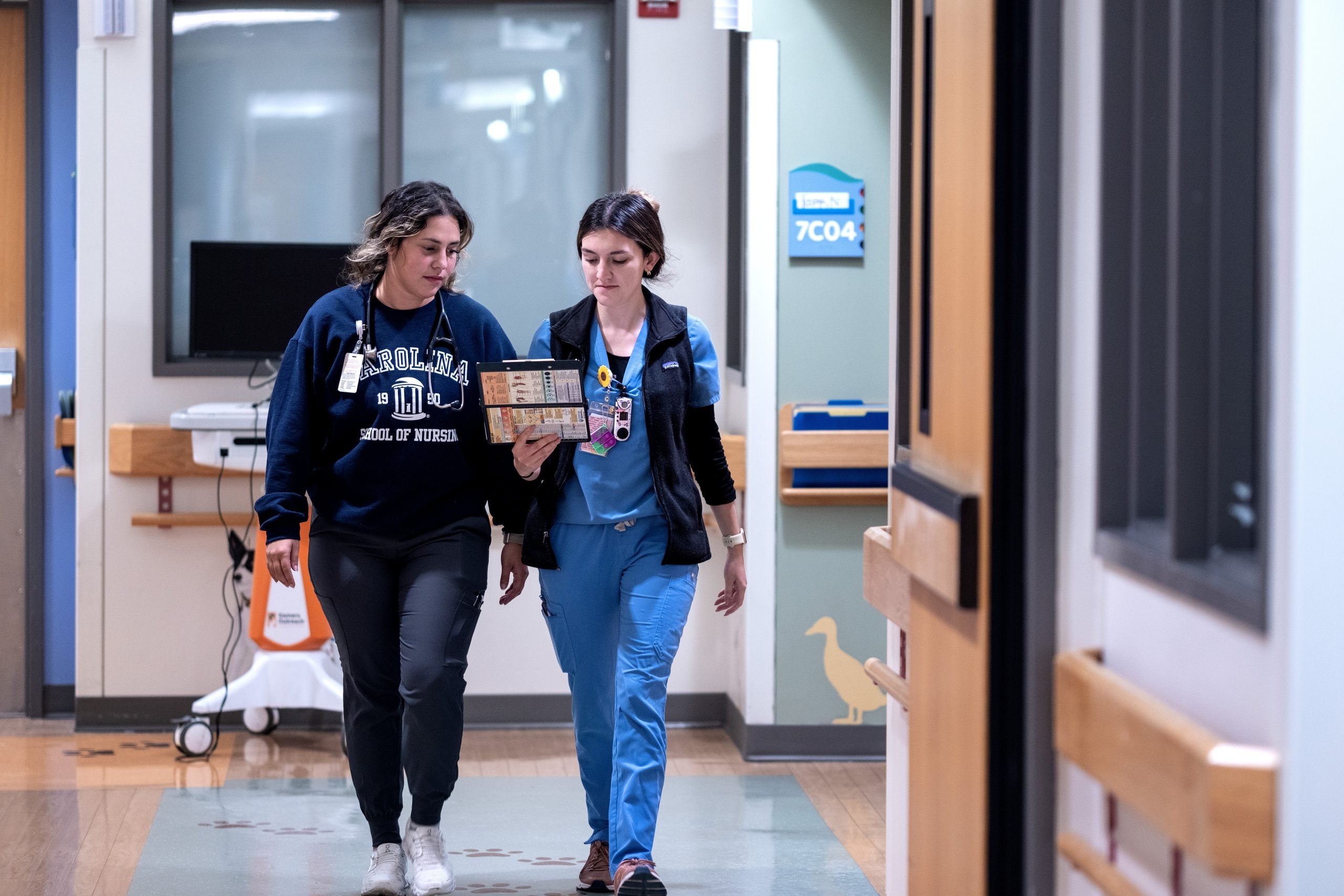 Two UNC-Chapel Hill nurses walking down the hallway of a hospital.