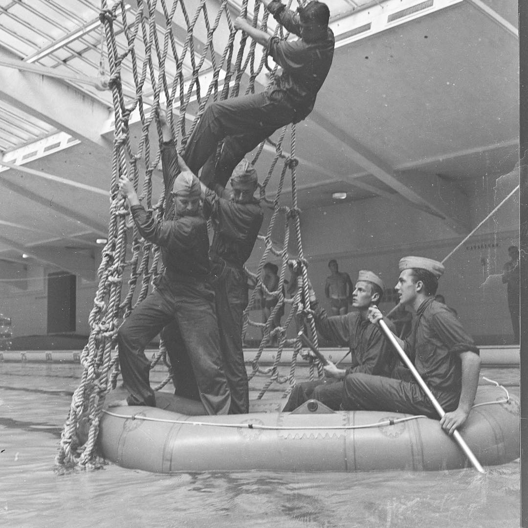 Black-and-white photo of five men doing Naval training exercises in Bowman Gray Memorial Pool on the campus of UNC-Chapel Hill in the 1940s.