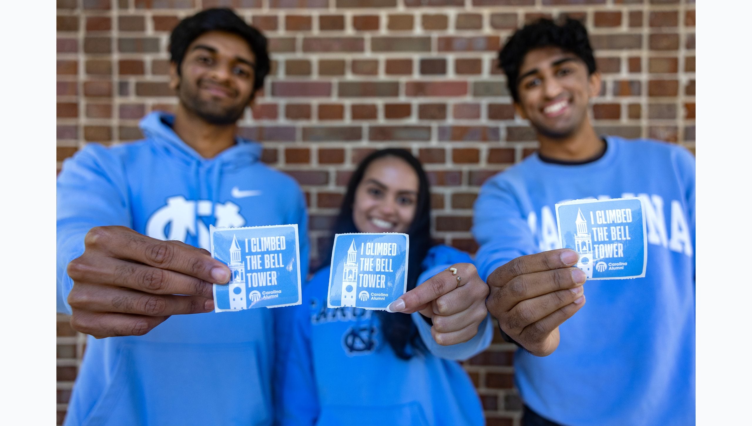 Three UNC-Chapel Hill students holding stickers that read: 
