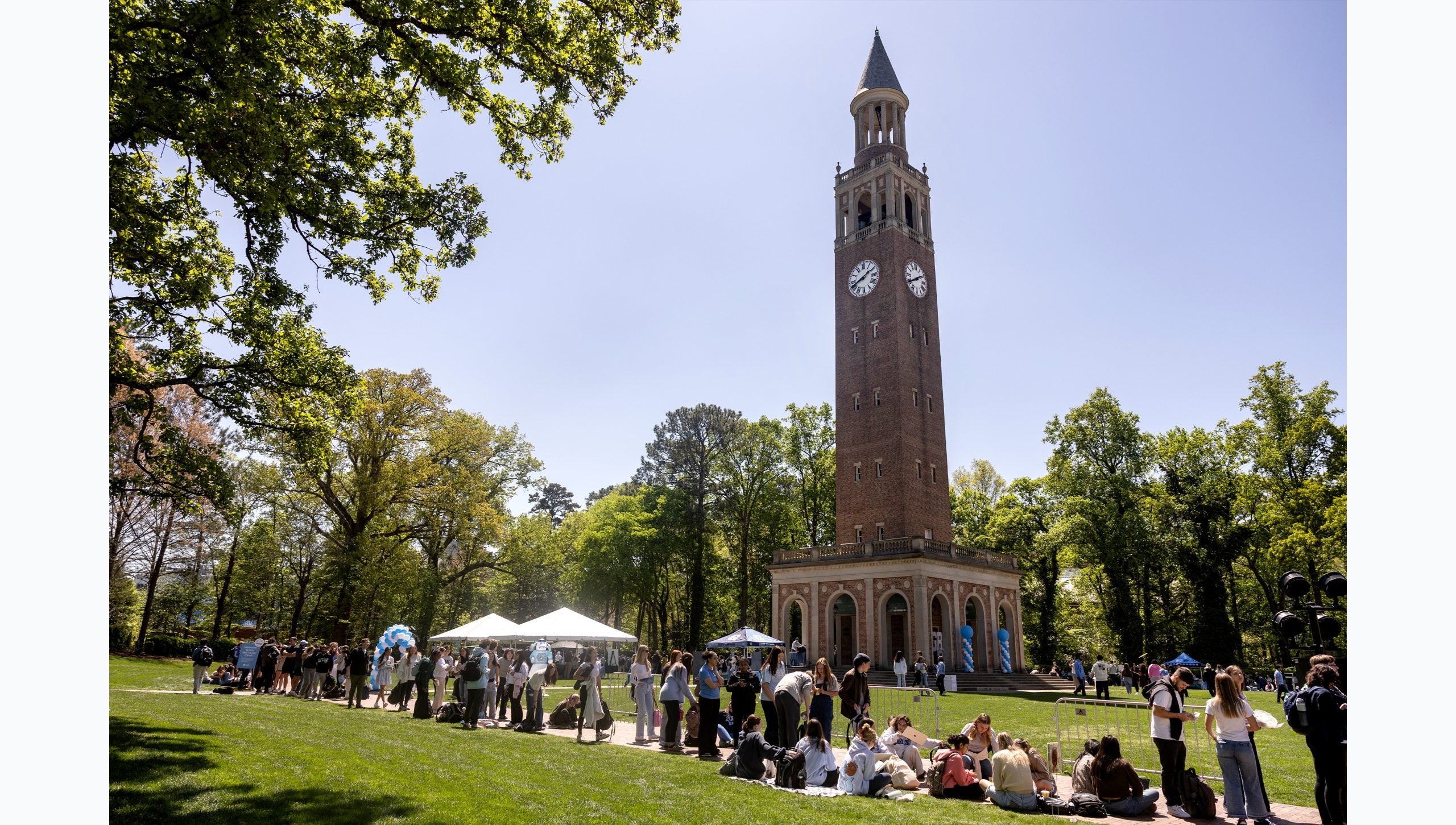 Image from a distance of UNC-Chapel Hill students waiting to climb the Bell Tower on the campus of UNC-Chapel Hill. The Bell Tower is seen in the background.