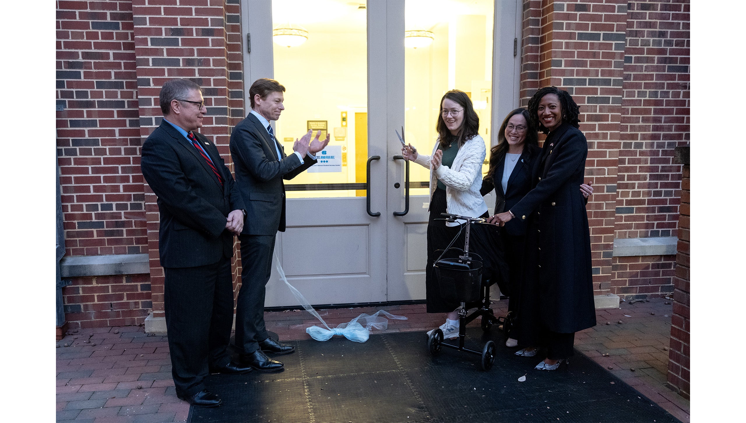 Five people — Rob Palermo, Lee H. Roberts, Roslyn Ward, Desirée Rieckenberg and Jocelyn Mitnaul Mallette — cutting the ribbon outside the door of the Military and Veteran Student Success Center during the grand opening event at UNC-Chapel Hill.