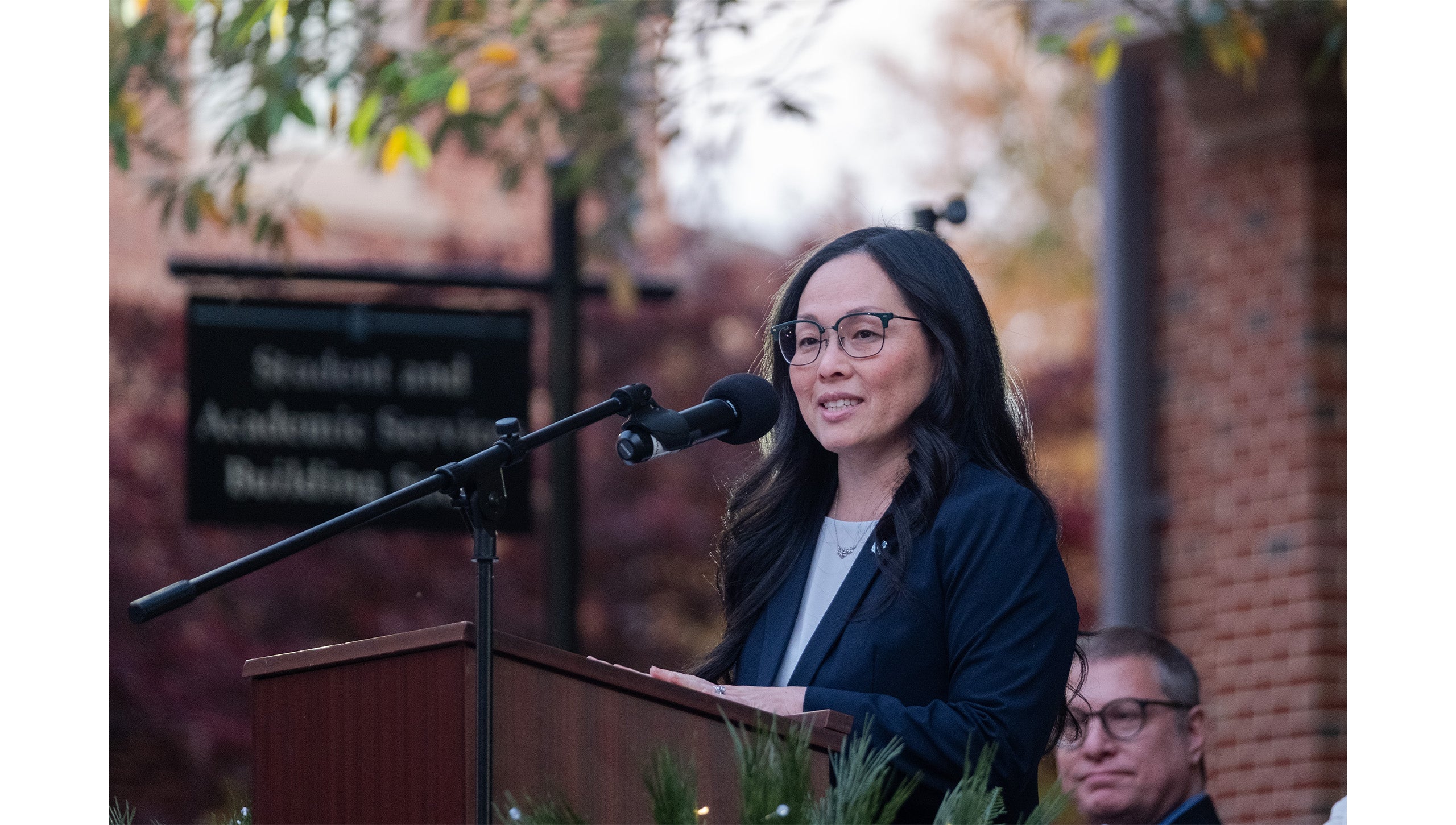 Desirée Rieckenber speaking into a microphone at a podium during the grand opening of the UNC-Chapel Hill Military and Veteran Student Success Center.