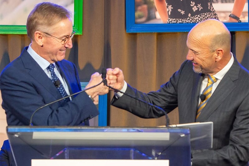 Dr. Wesley Burks and Dr. Craig Albanese fist-bumping at a podium at an event announcing a new children's hospital in North Carolina that will be run by UNC Health and Duke Health.