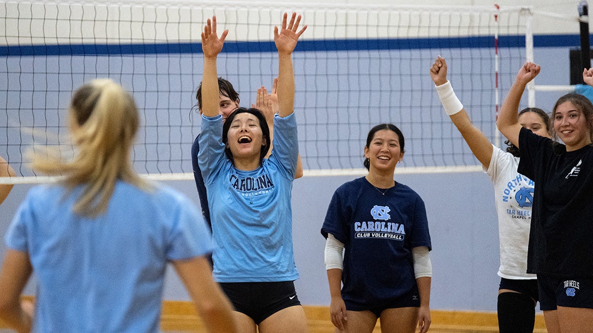 Club volleyball players from UNC-Chapel Hill celebrating after a point in practice in a gym.