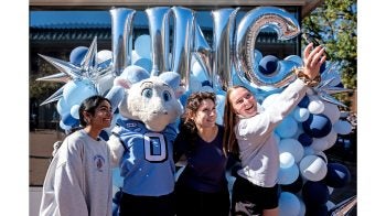 Three UNC-Chapel Hill employees taking a selife with Rameses Jr., one of Carolina's ram mascots.