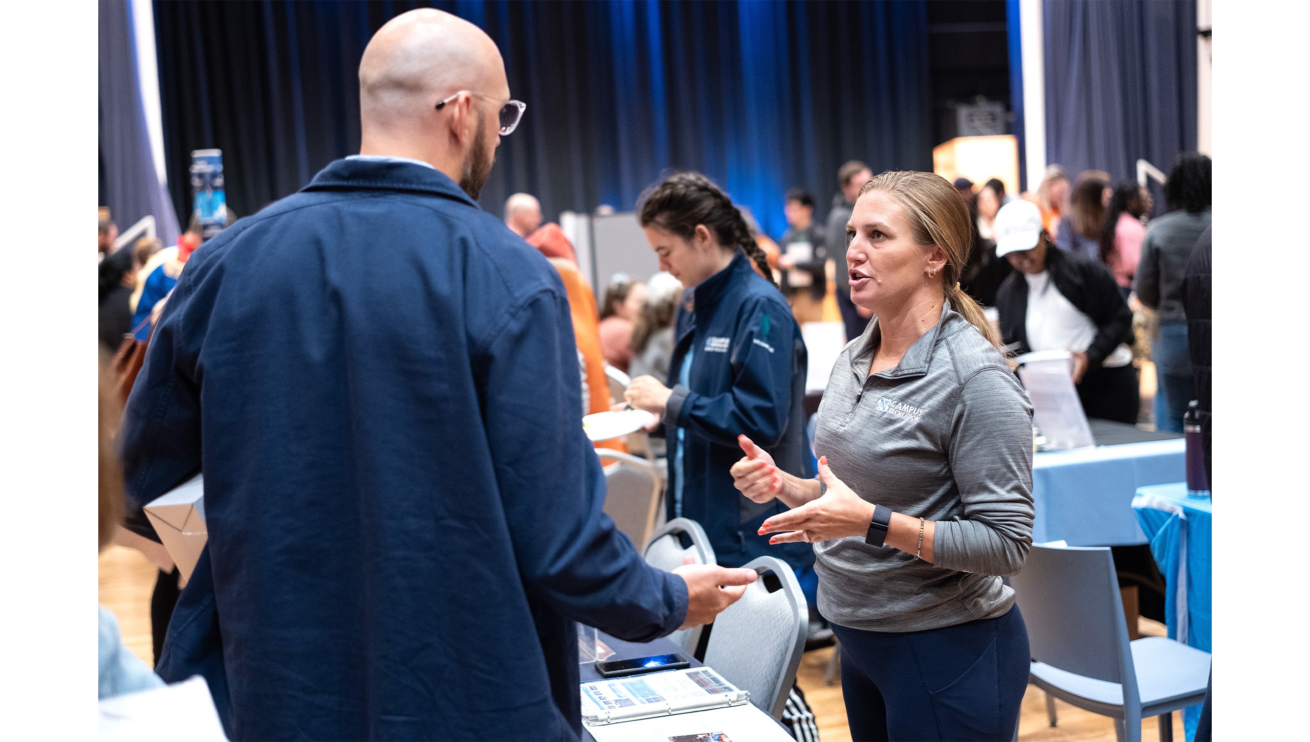 Two UNC-Chapel Hill employees talking to each other inside the Frank Porter Graham Student Union.