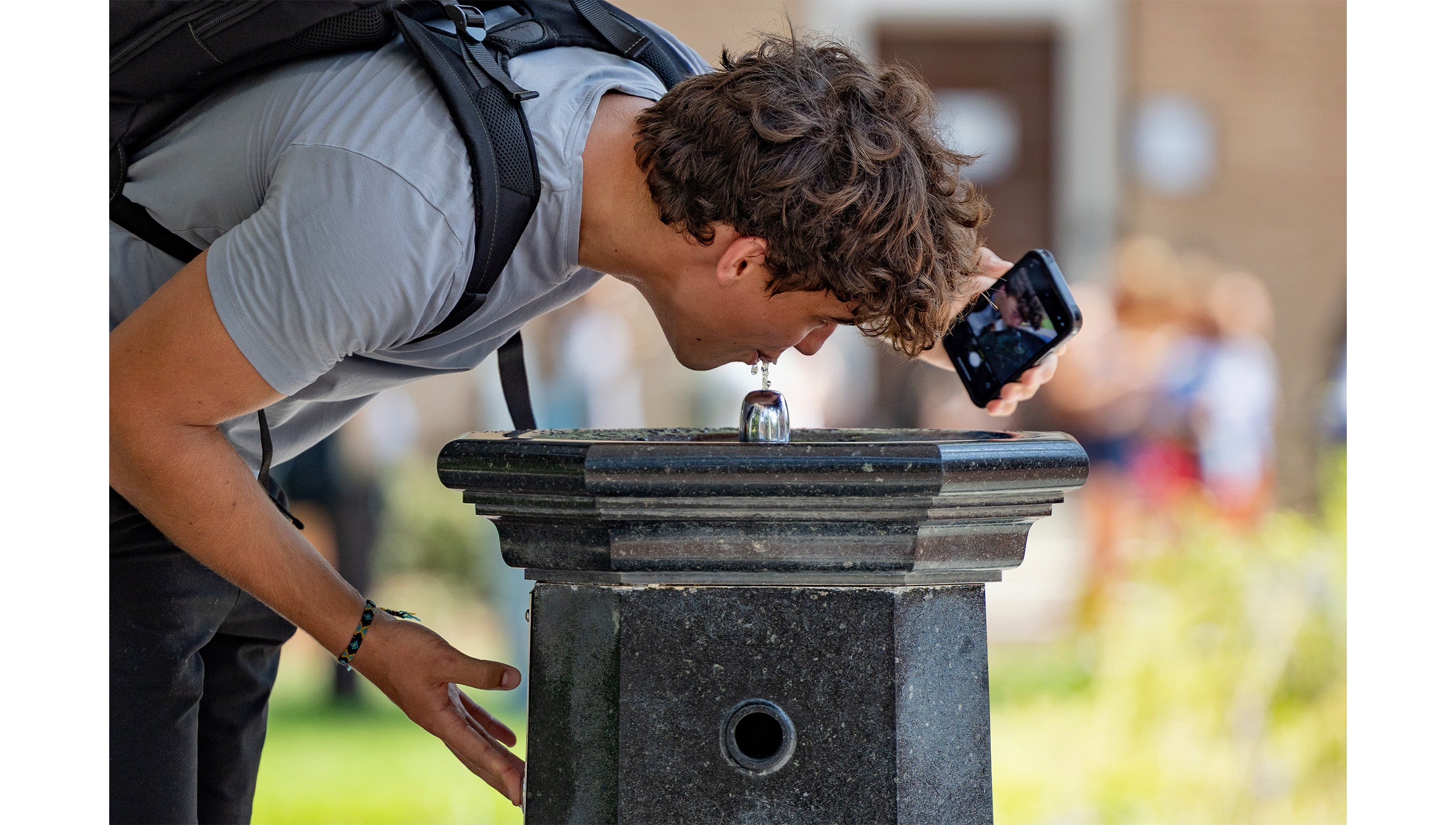 UCN-Chapel Hill student taking a selfie with iPhone while sipping from the fountain of the Old Well.