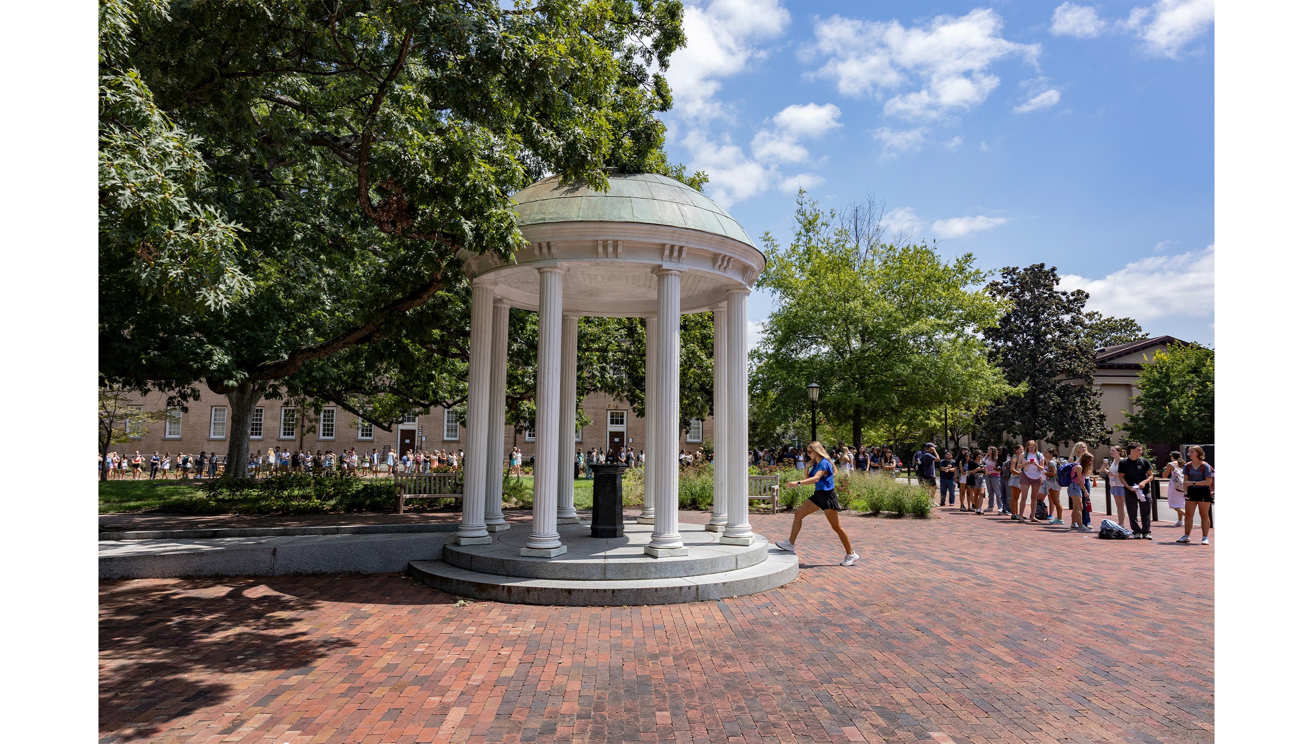UNC-Chapel Hill student approaching the Old Well to take a sip as a long line is seen behind her.