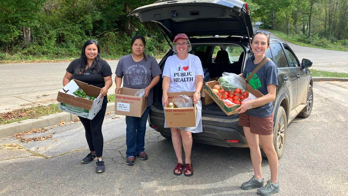 Four students holding supplies in boxes.