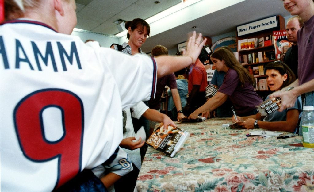 Mia Hamm signing books and talking with young children in a photo from 1999.