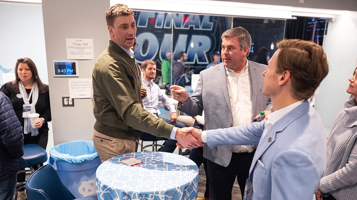 Tyler Hansbrough shakes hands with Chancellor Lee H. Roberts at a Carolina basketball game in January 2024.