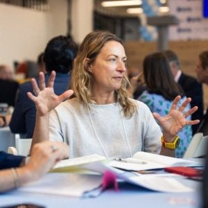Woman speaking to colleagues at a round table.