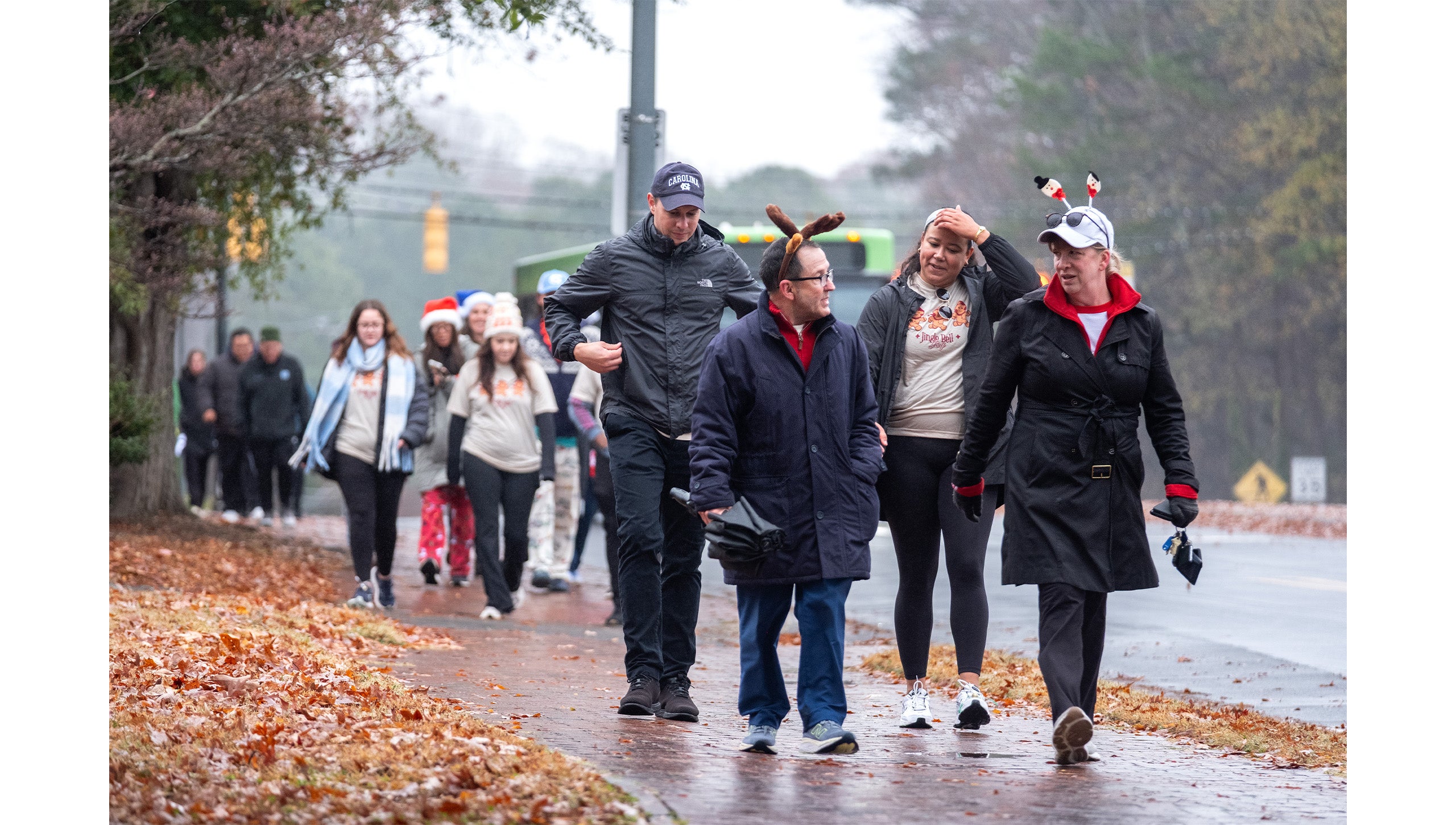 UNC-CHapel Hill employees walking down a brick sidwalk during the Jingle Bell Jog, some wearing festive costumes and outfits.