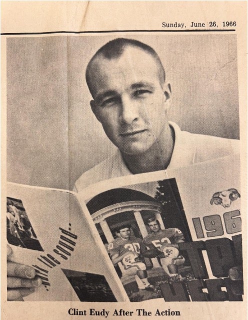A newspaper clipping shows a photo of Capt. John Eudy reading a magazine.