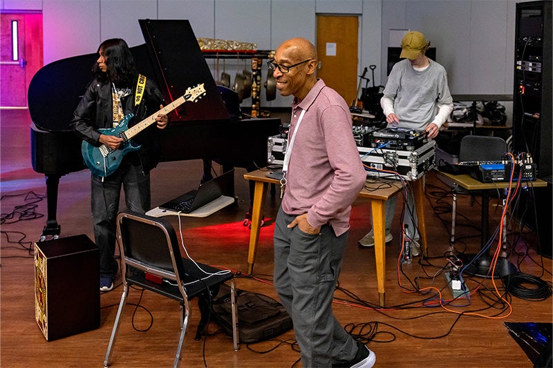 Kerwin Young smiling as students in a Hip-Hop Ensemble gather near their instruments.