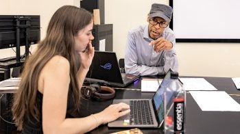 Kerwin Young instructing a student in his beat making course as she looks at her laptop.