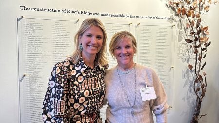 Molly Painter and Kathy Izard posing for a photo in front of a wall with painted text reading, 
