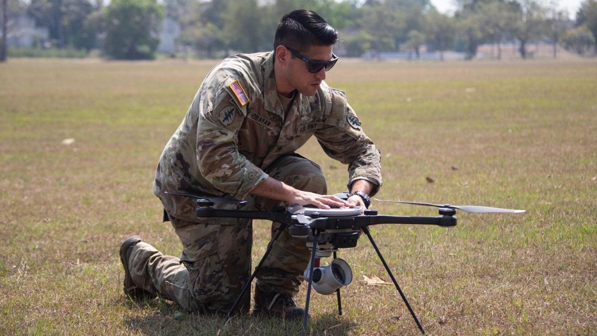 LeBon Hobayan fixing a drone in a field.