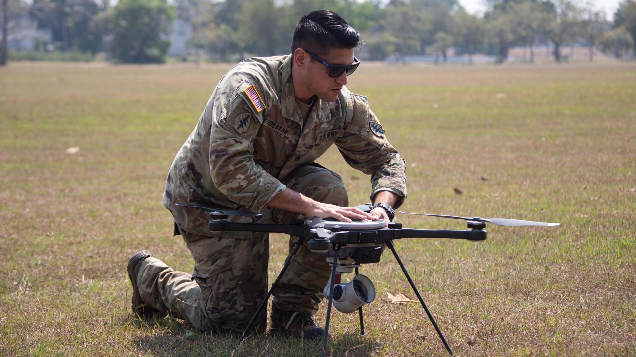 LeBon Hobayan fixing a drone in a field.