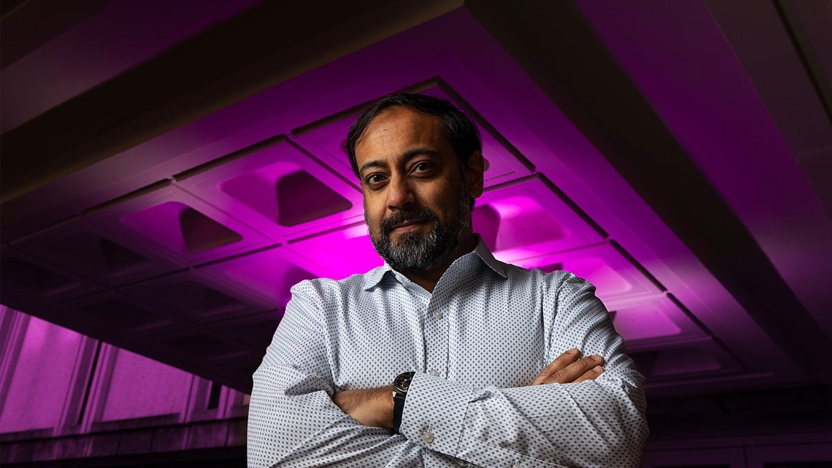 Nabarun Dasgupta poses for a photo with his background bathed in purple light.