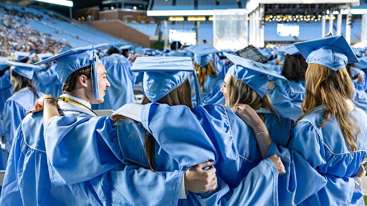 Graduates hug while singing Hark the Sound at 2025 Spring Commencement.