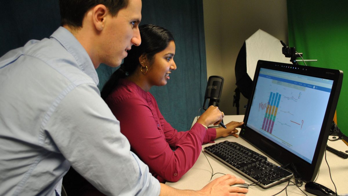 Two students working and looking at a computer.