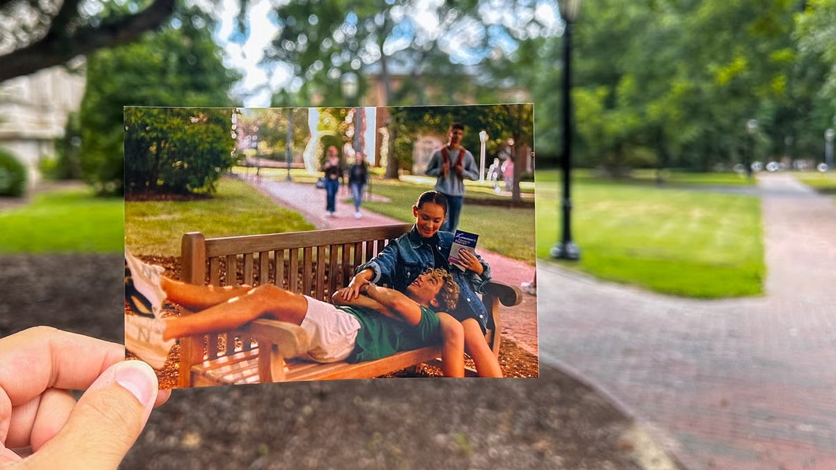 A person holds a photo of a scene from 