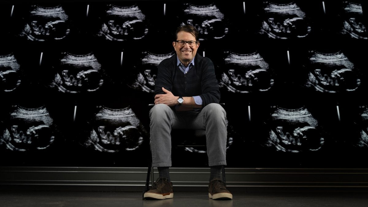 Jeffrey Stringer sitting in front of a wall of ultrasounds.