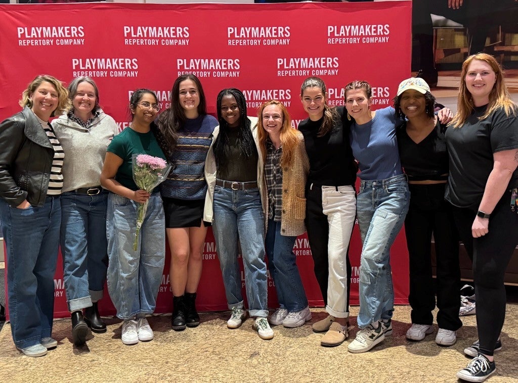 Actors and athletes posing in front of playmakers sign.