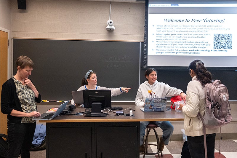 A group of Peer Tutoring employees and a student checking in at her tutoring appointment in a classroom on the campus of UNC-Chapel Hill.