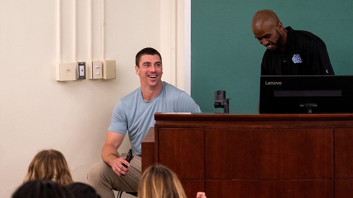 Tyler Hansbrough and Livis Freeman talk at the front of a classroom in Carroll Hall.