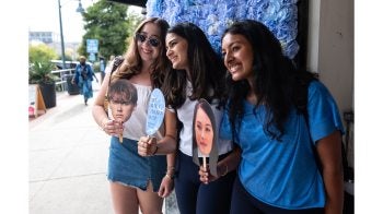 Three UNC-Chapel Hill students holding up head cutouts of characters from “The Summer I Turned Pretty” outside the Varsity Theatre.