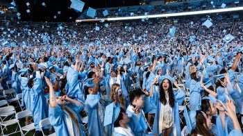 Graduates toss their caps at the end of Spring Commencement