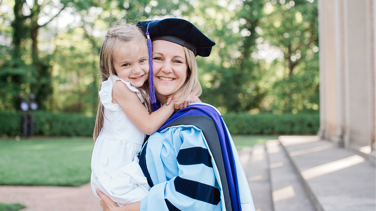 Brittany in Carolina Blue and black regalia Akers holding and hugging her daughter.