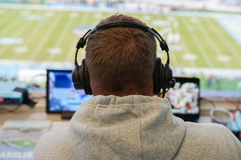Bryn Renner sits behind two monitors as he watches the Carolina football game providing commentary.
