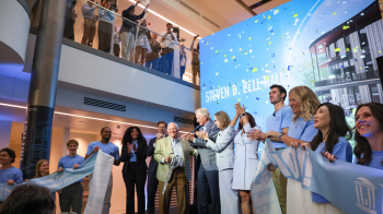 Crowd applauding in front of Bell Hall poster.