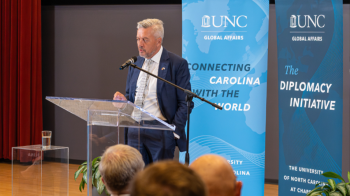 Finnish Consul General Jarmo Sareva stands at a podium speaking to a group of people at the Diplomatic Discussion event help on U.N.C. campus.
