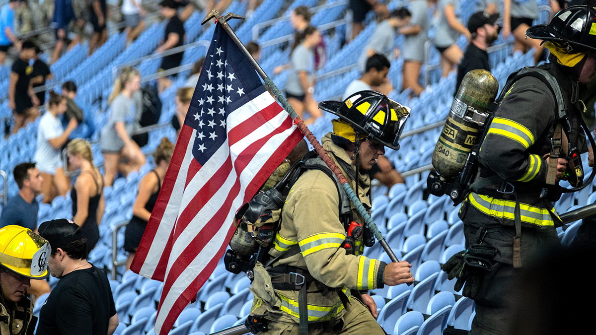 Firefighter walking up Kenan Flagler steps while holding American flag.