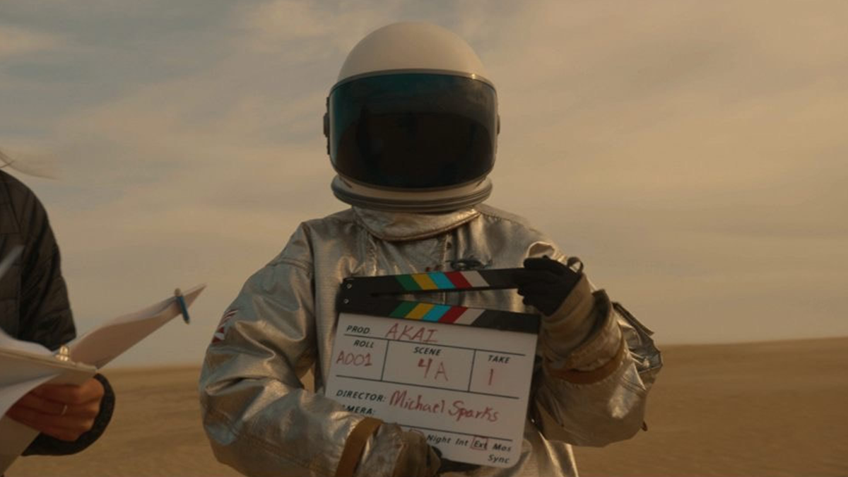 An astronaut holding a slate board that reads 