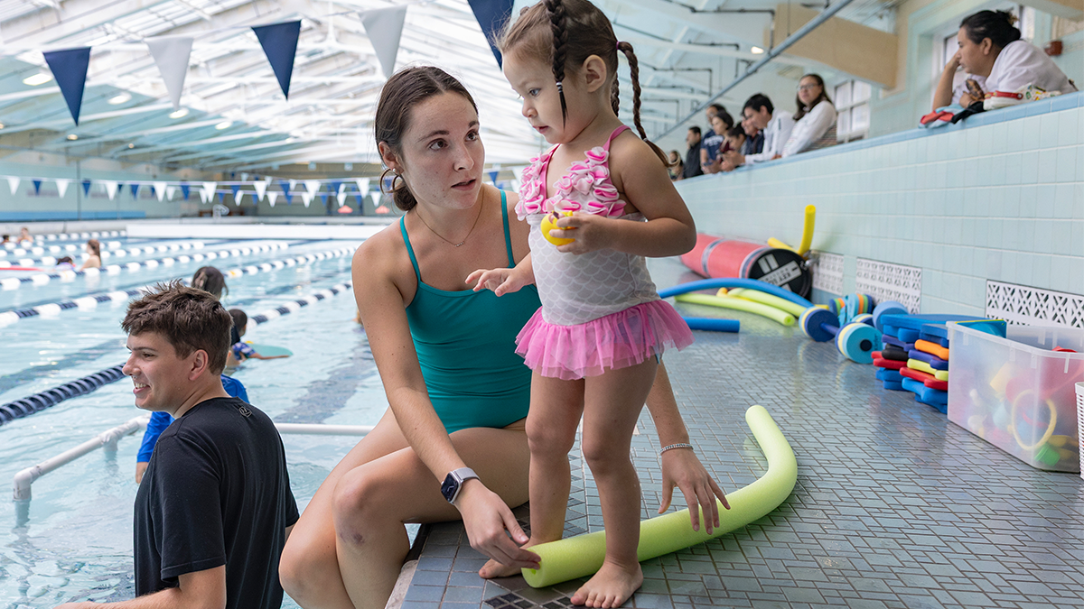 Swimming instructor working with student.