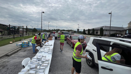 Volunteers wearing vests helping individuals in cars.