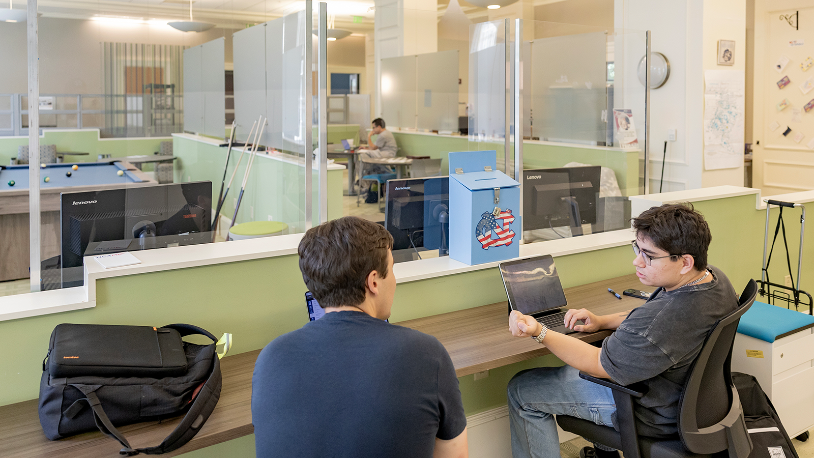 Two students working on a project while sitting in the student veterans space.