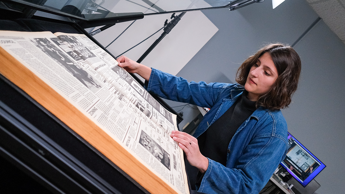 Woman examining vintage newspaper.