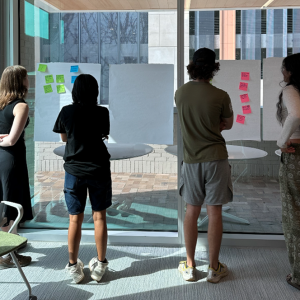 Four individuals examining sticky notes on boards.