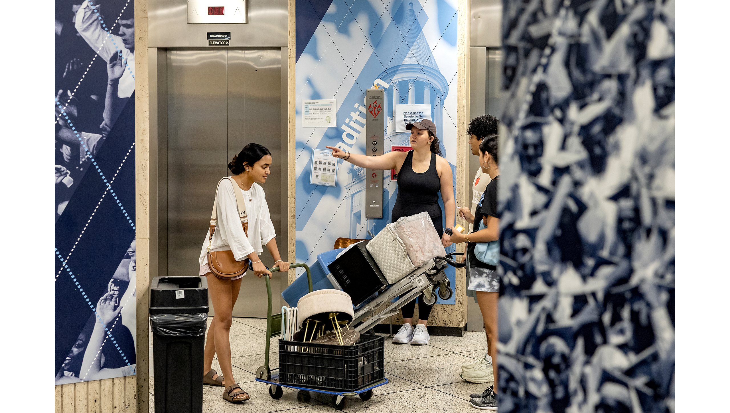 Students with carts full of room decor in hallway.