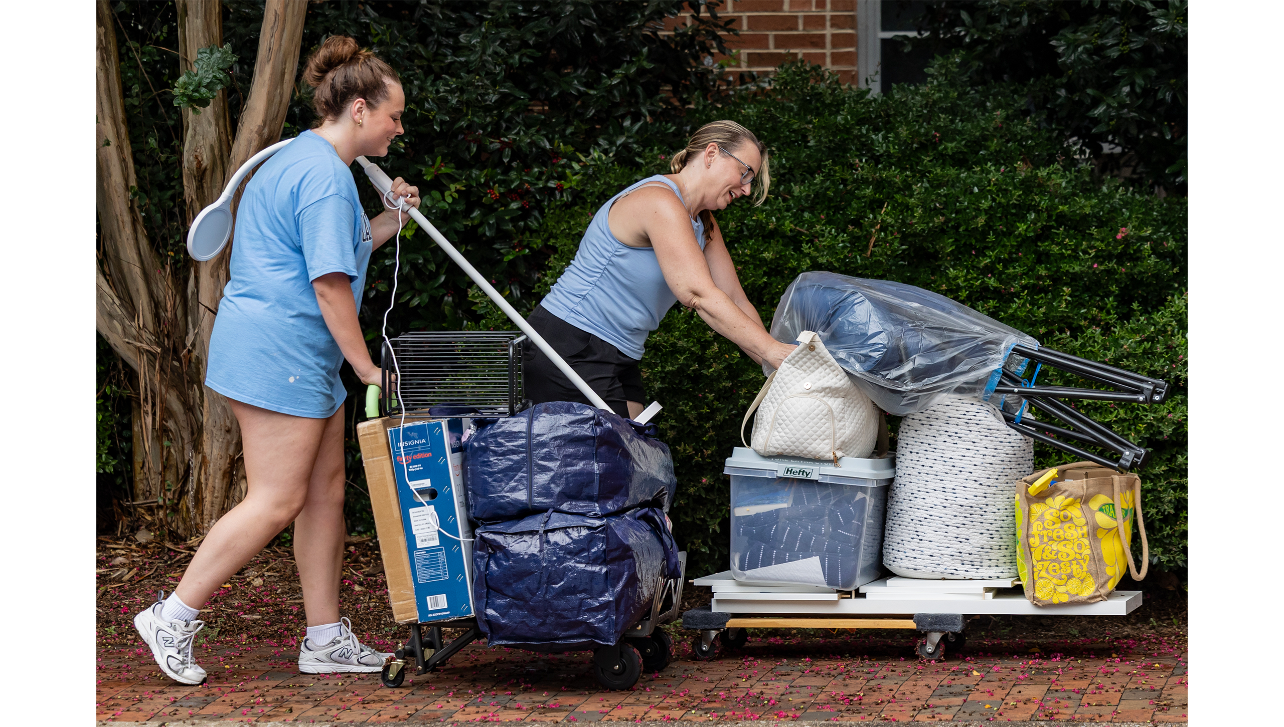 A mother and a daughter pushing carts of bags.