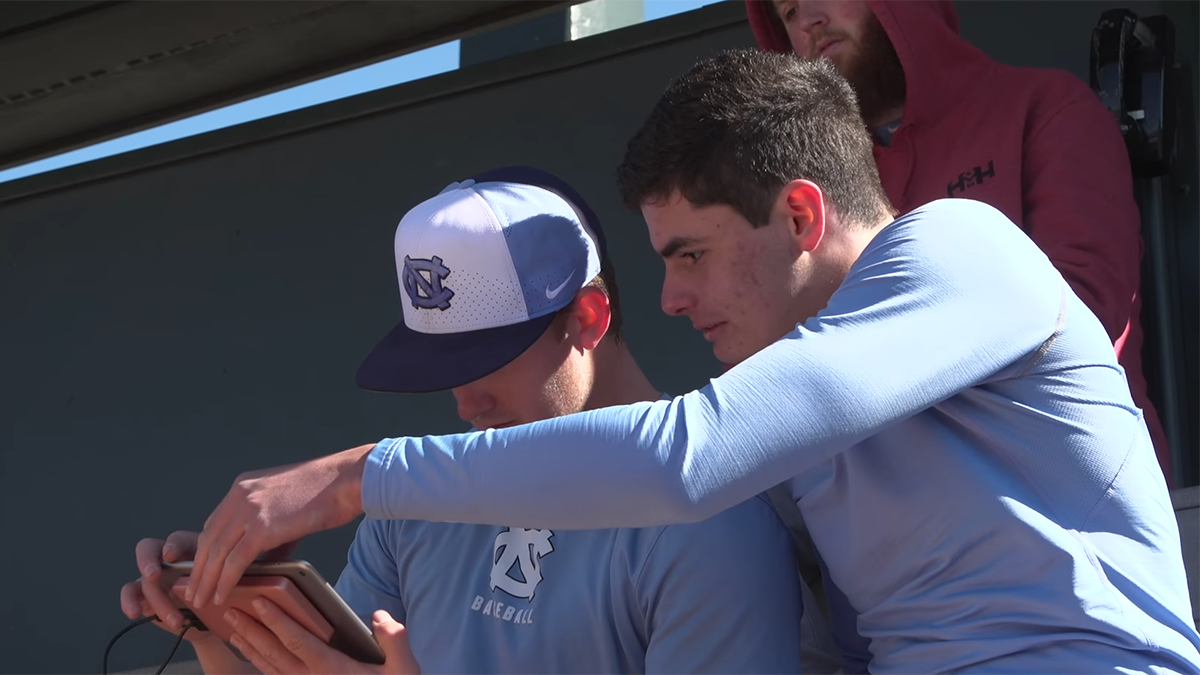 Micah Daley-Harris shows holds a screen while a baseball looks at it.