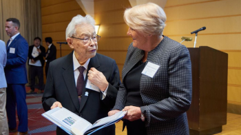 Barbara Stephenson and Taketo Furhata holding a book and speaking to each other.